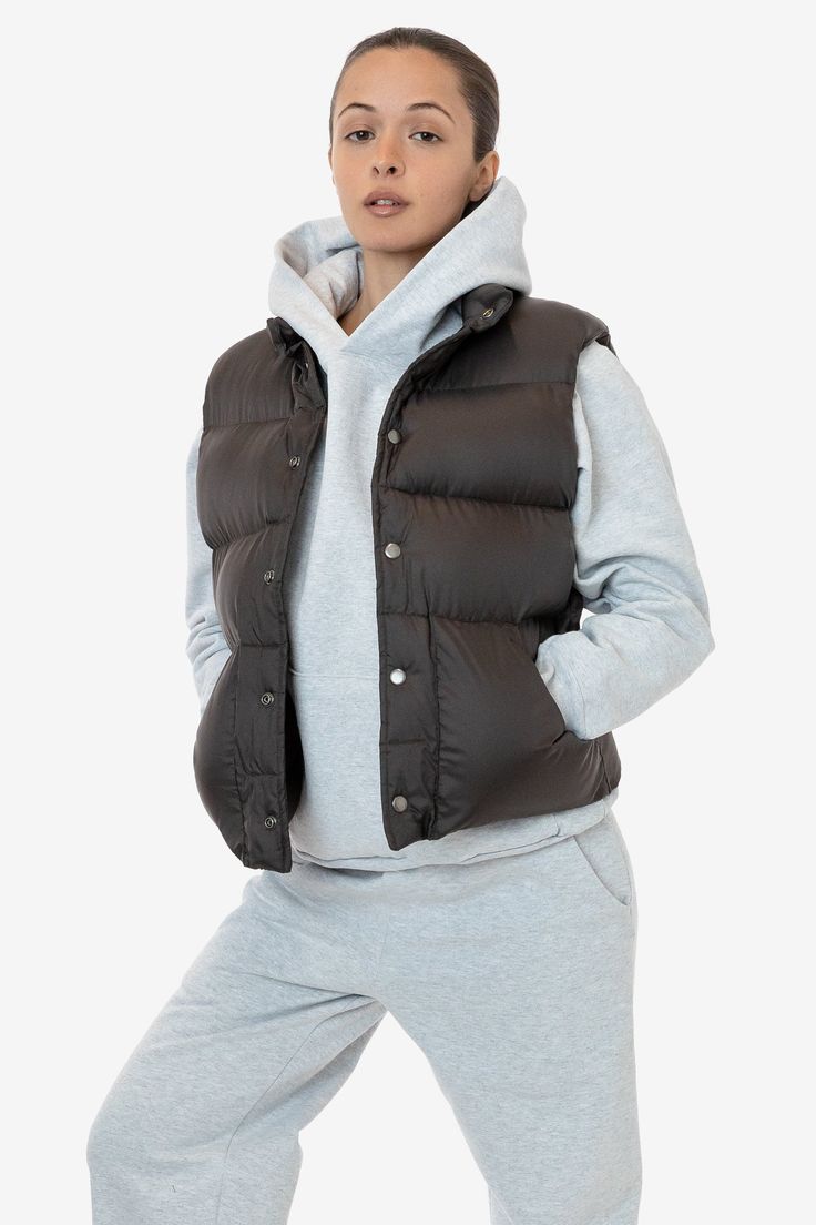 This made in U.S.A. puffer vest is the perfect layering piece for Los Angeles winters. Composed of a super fluffy polyester filling with a 100% nylon shell, this style features a reinforced snap-button closure, and 2 large pockets. We gave this style a wide, boxy fit with a mockneck for essential warmth. Try sizing up for an even more oversized fit. Made in Los Angeles, Calif. Our experienced sewers earn up to $25 an hour and no less than $16; additionally workers have healthcare benefits for le Nylon Winter Vest Outerwear, Winter Nylon Vest Outerwear, Cold Weather Puffer Vest, Sporty Sleeveless Puffer Outerwear, Sleeveless Down Puffer Vest, Sporty Winter Vest For Layering, Solid Puffer Vest For Cold Weather, Nylon Vest For Layering In Fall, Cold Weather Solid Puffer Vest