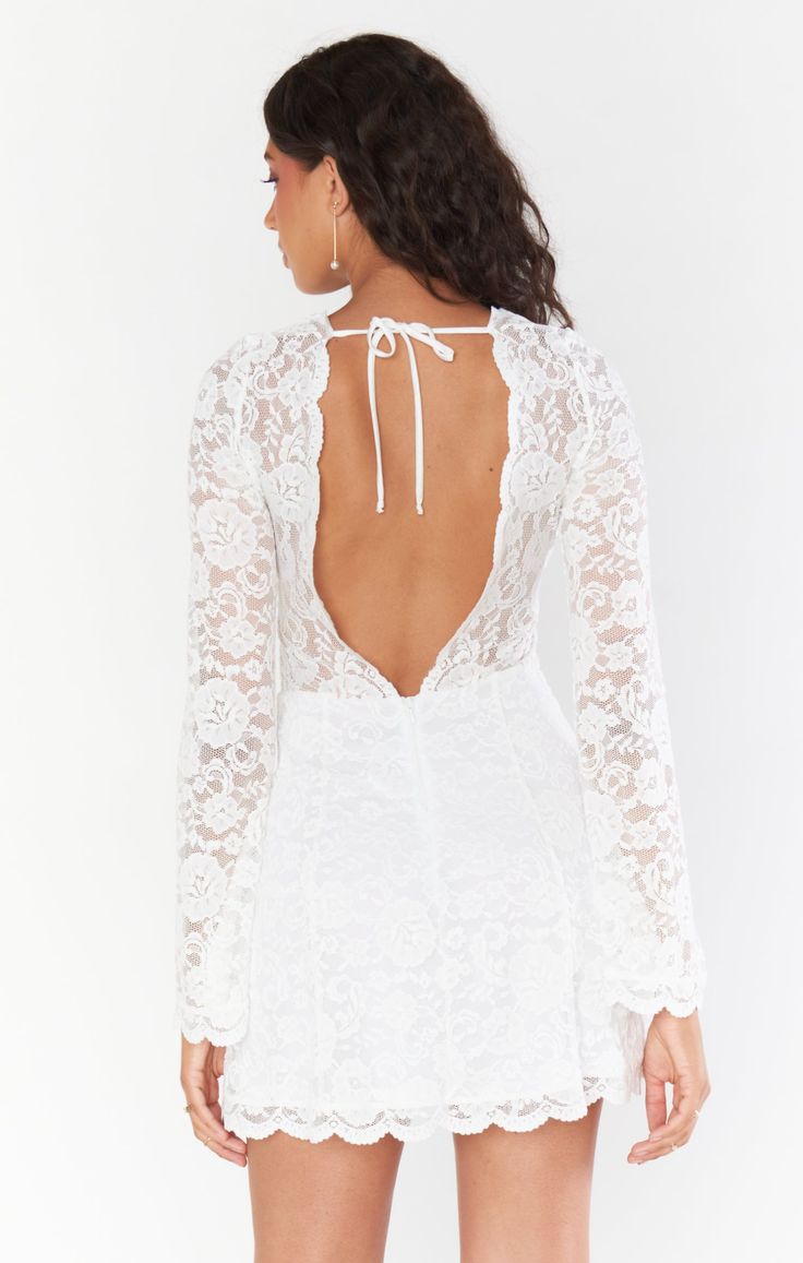 a woman wearing a white lace dress with open back