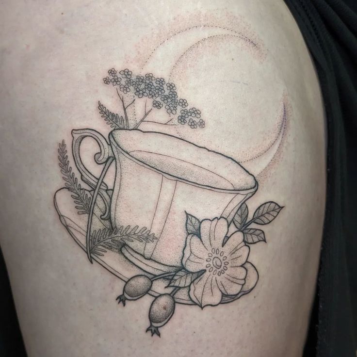 a woman's thigh with a cup and flowers on it