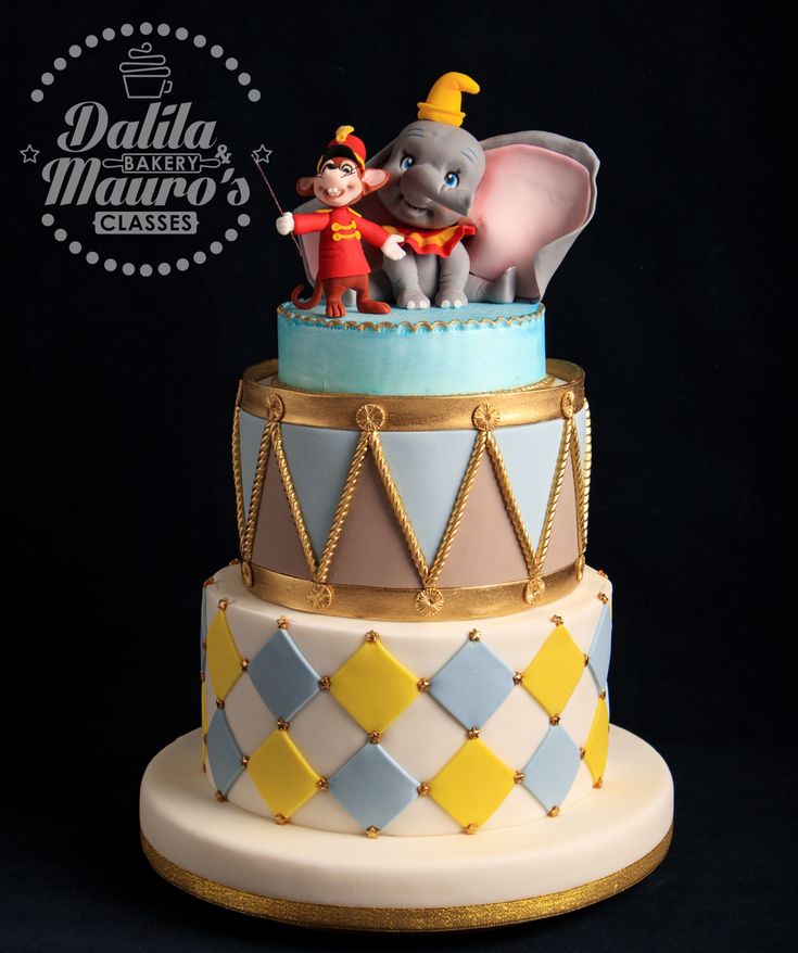 there is a three tiered cake decorated with an elephant and circus characters on top