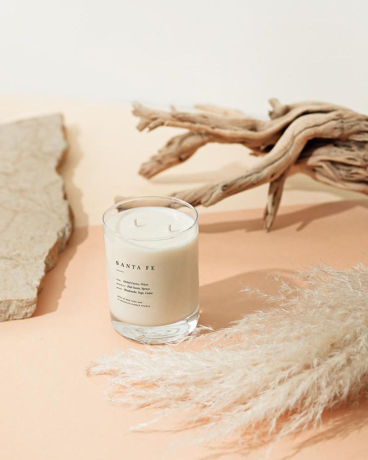 a white candle sitting on top of a table next to a piece of driftwood