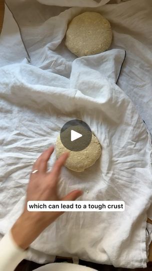 a person reaching for some food on top of a white cloth covered bed spread out in front of them