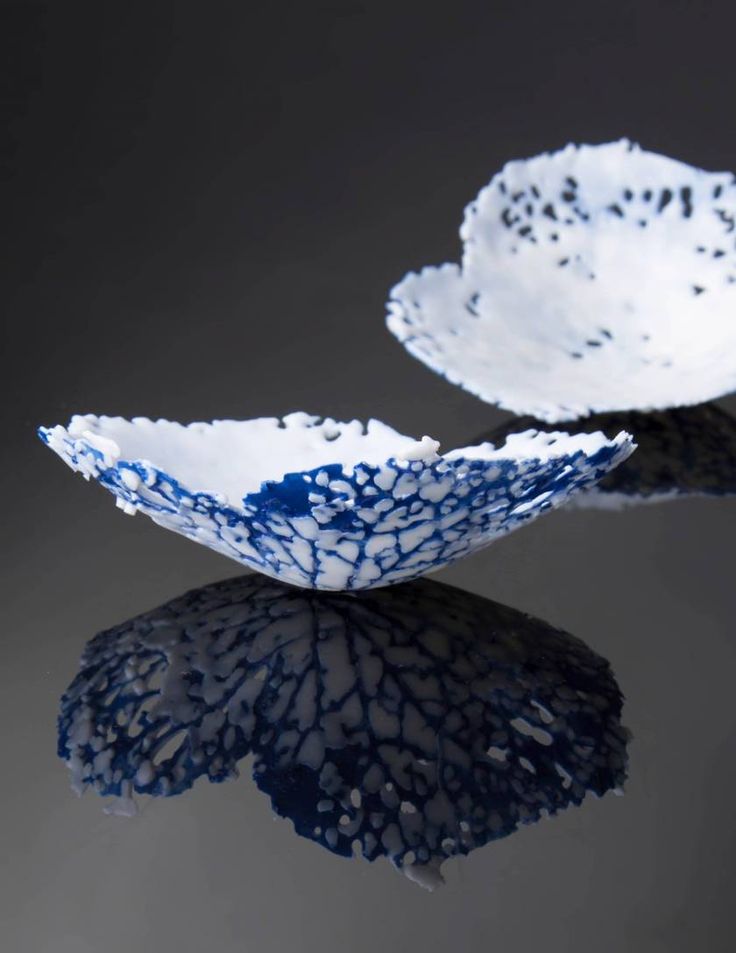 two blue and white bowls sitting on top of a black tablecloth covered surface with water droplets