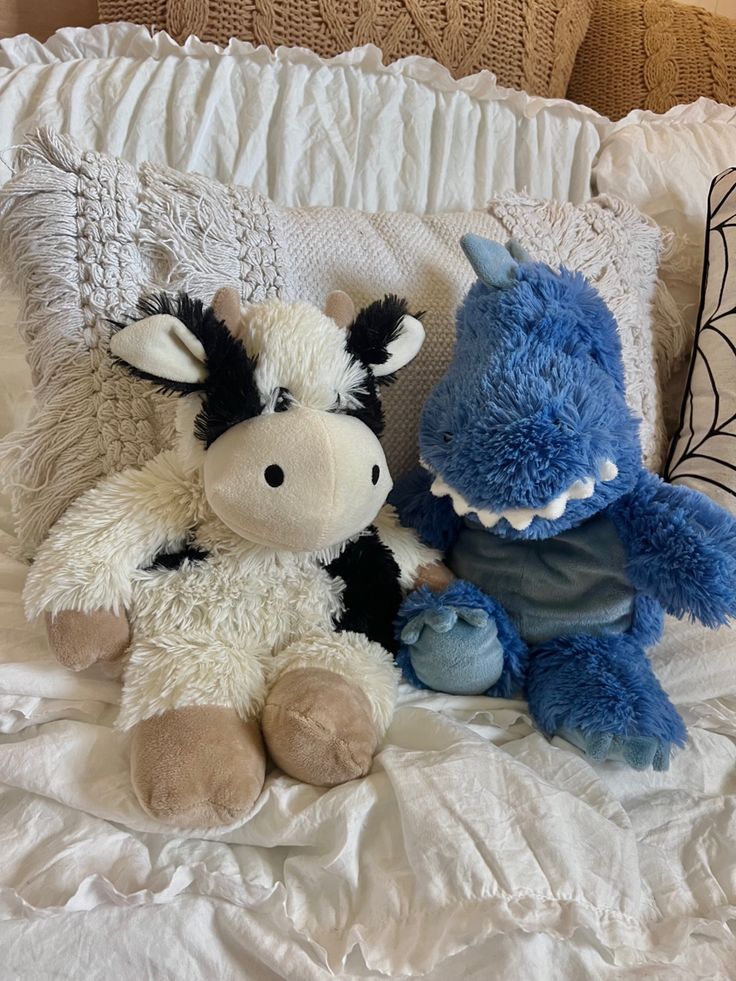 two stuffed animals sitting on top of a bed