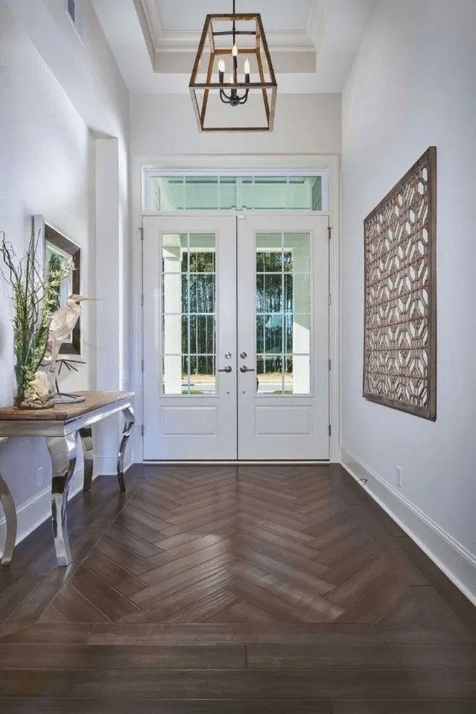 a hallway with two doors and a chandelier hanging from it's ceiling