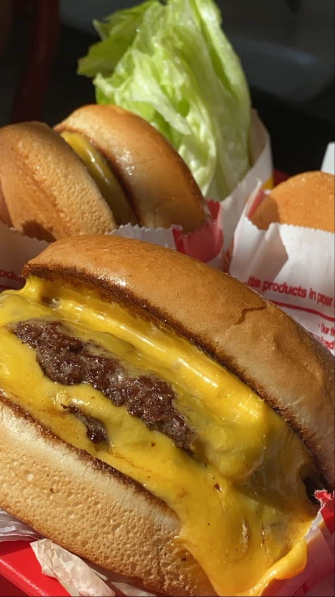 two cheeseburger sandwiches with lettuce on the side