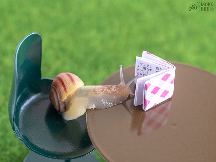 a snail is eating some food on a small table in the grass with it's tail sticking out