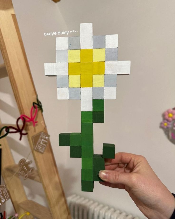 a person holding up a piece of paper that looks like a cactus with yellow and white flowers on it