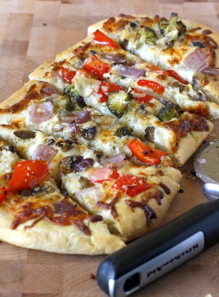 a pizza sitting on top of a wooden cutting board next to a knife and pepperoni