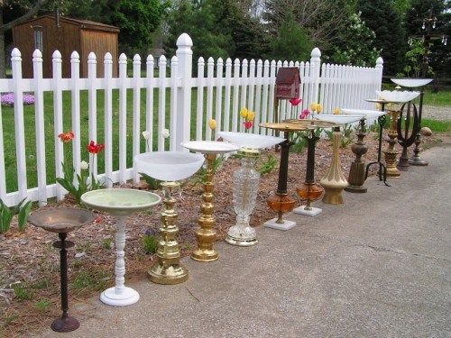 a white picket fence with lots of different types of birdbathes on top of it