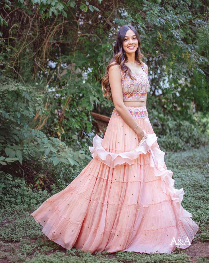 A frilled pink skirt paired with a unique scallop-edge blouse. It is paired with a ruffle dupatta. DELIVERY TIME Please allow 8-12 weeks for your outfit to arrive. FABRIC DETAILSCrepe. Professional cleaning only. Designer Floor-length Ruffled Choli, Anarkali Lehenga With Ruffles And Traditional Drape, Anarkali Lehenga With Traditional Drape And Ruffles, Traditional Drape Georgette Lehenga With Ruffles, Traditional Georgette Lehenga With Ruffles, Fitted Georgette Gown With Ruffles, Wedding Lehenga With Ruffles In Traditional Drape, Traditional Lehenga With Ruffles For Reception, Traditional Drape Lehenga With Ruffles For Wedding