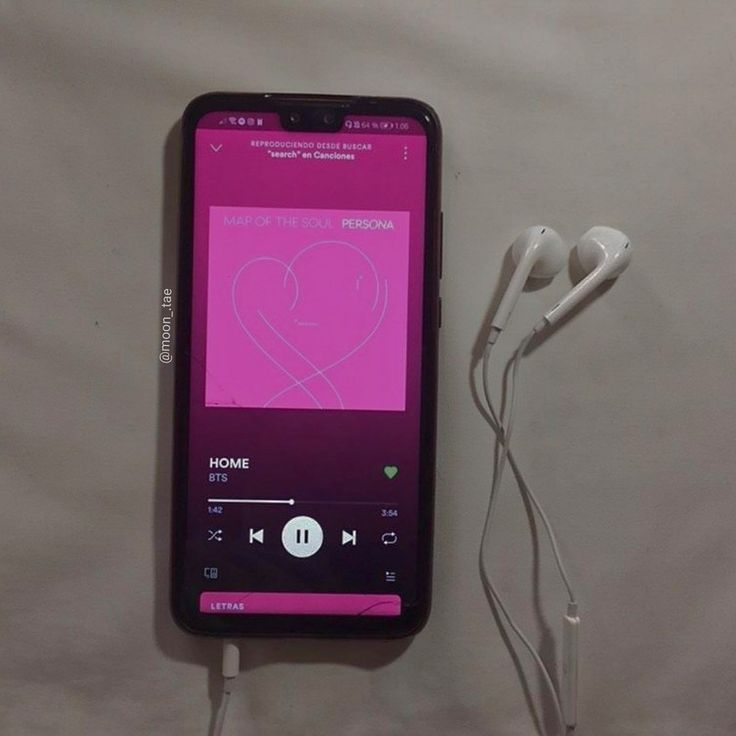 an mp3 player with ear buds plugged into it sitting on a white surface next to headphones