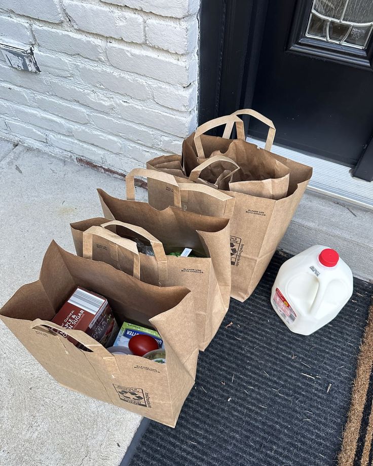 three brown paper bags sitting on top of a door mat