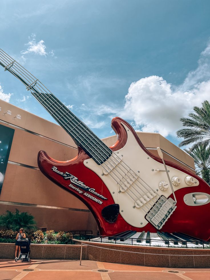 a red and white guitar sculpture in front of a building