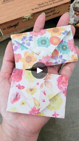 someone is holding an origami envelope with flowers on it and the paper has been folded