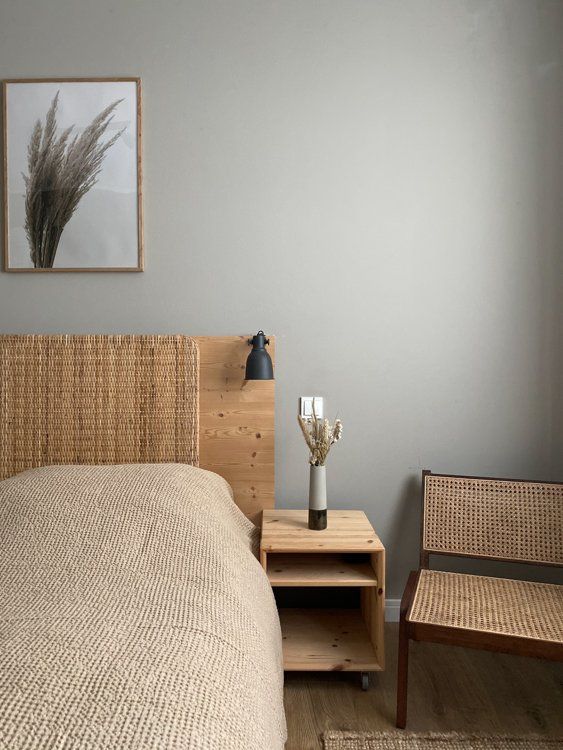 a bed sitting next to a wooden table with two vases on top of it