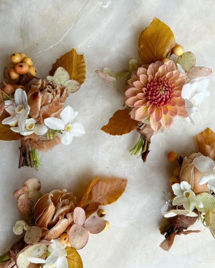 four different types of flowers and leaves on a marble surface