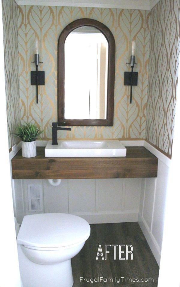 a white toilet sitting under a bathroom mirror next to a wooden counter top with a potted plant on it