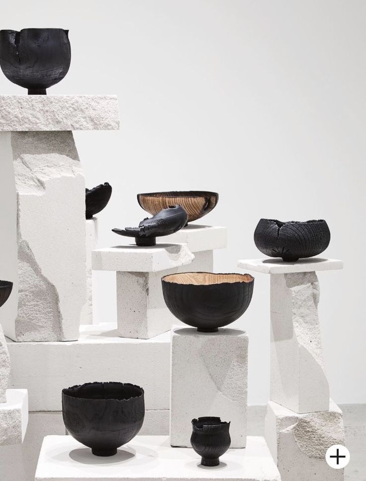 black and white bowls are stacked on top of each other in front of a white wall