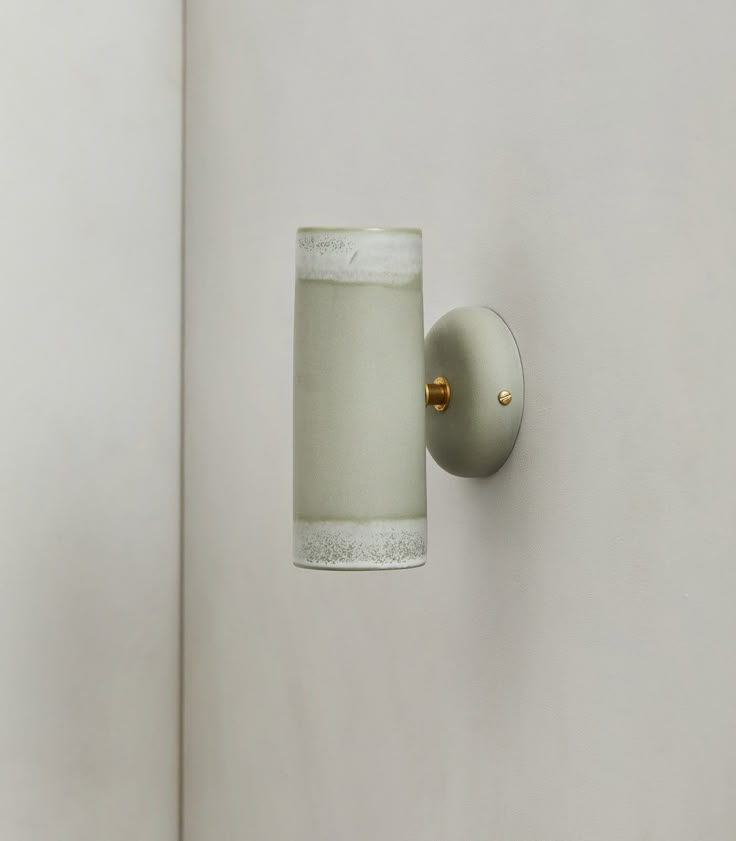 a light that is on the side of a white wall next to a cup with something in it