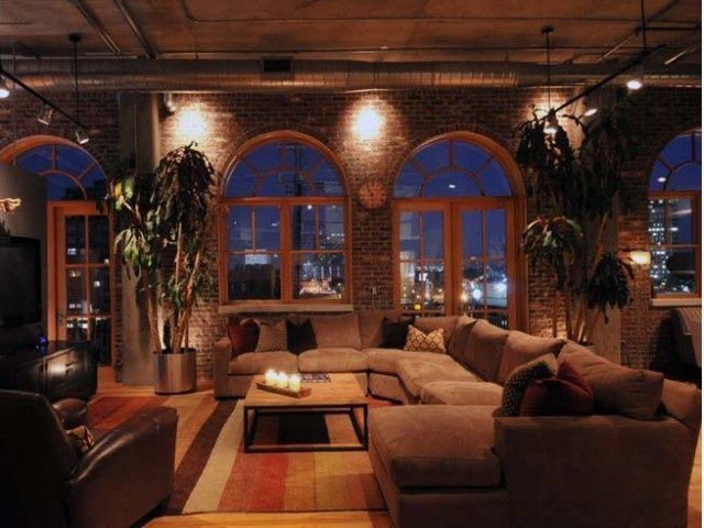 a living room filled with lots of furniture next to tall windows and potted plants