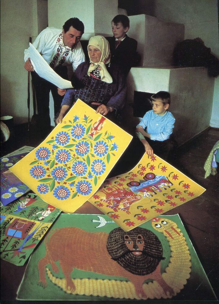 a group of people standing next to each other in front of paintings on the floor