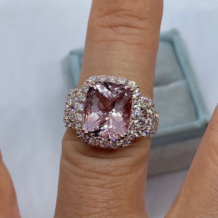 a woman's engagement ring with an oval pink diamond surrounded by round brilliant pave diamonds