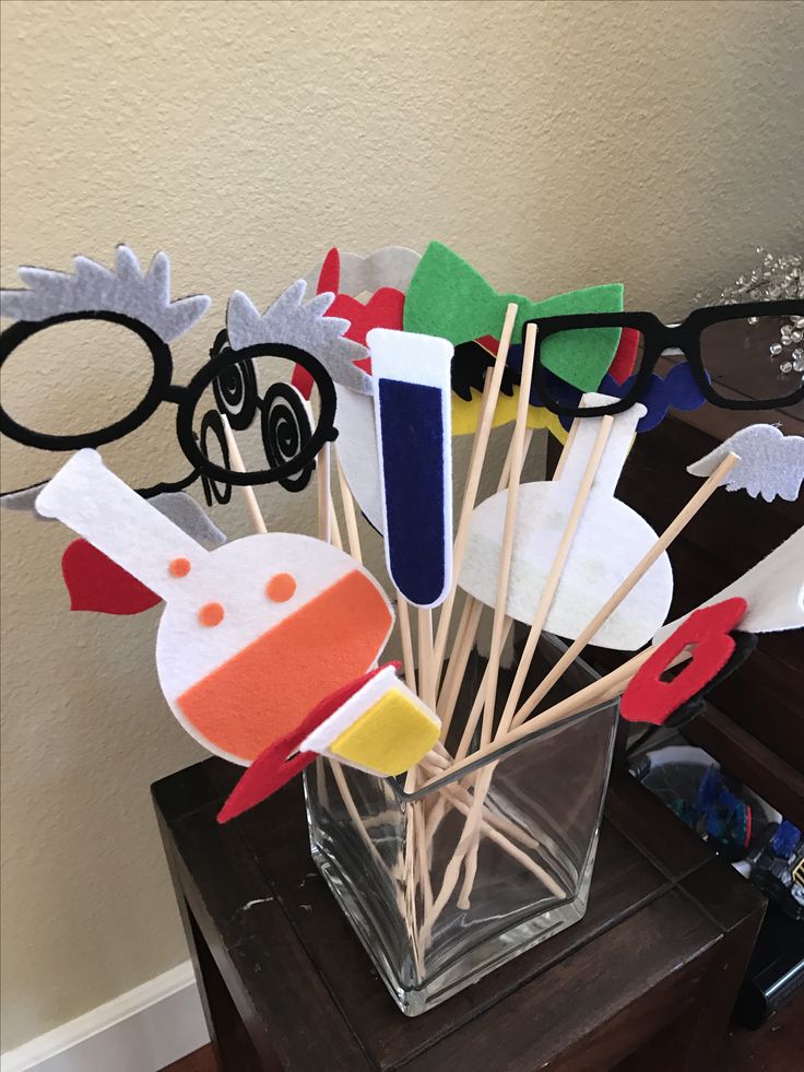 a vase filled with toothpicks on top of a wooden table next to eyeglasses