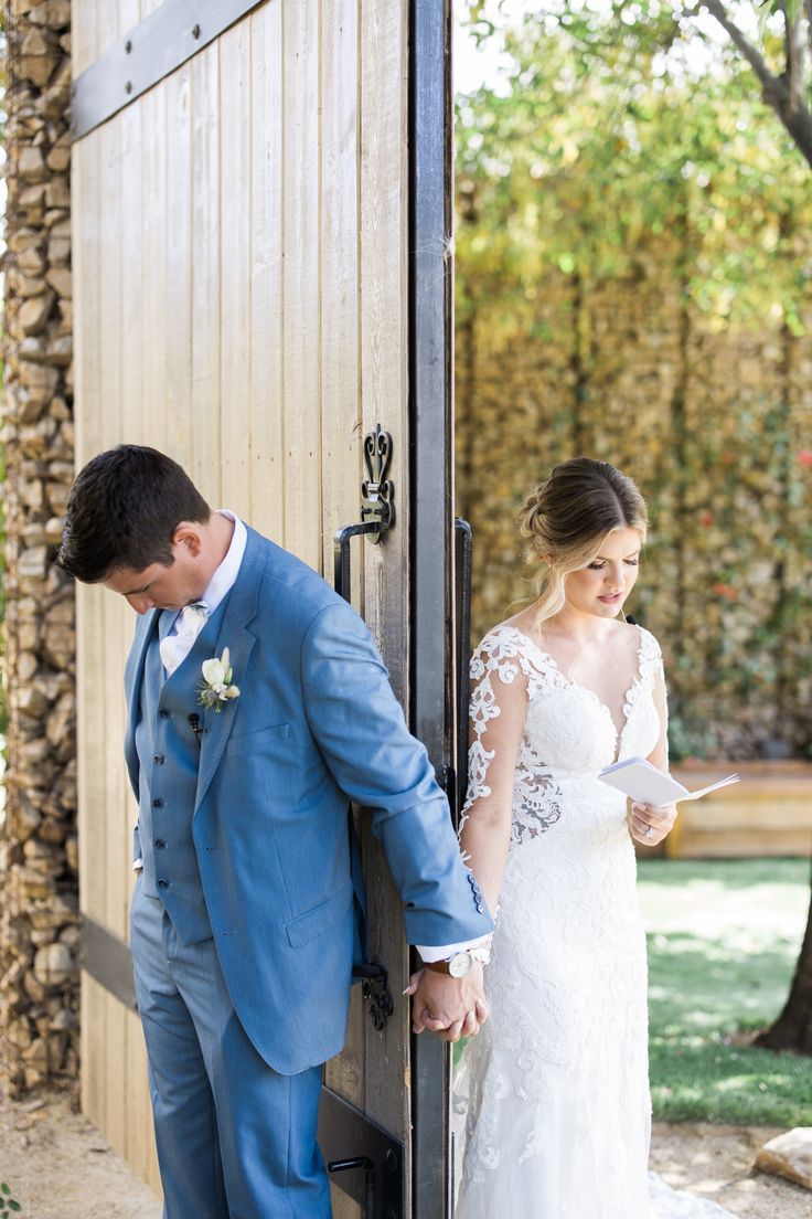 the bride and groom are holding hands as they stand in front of an open door