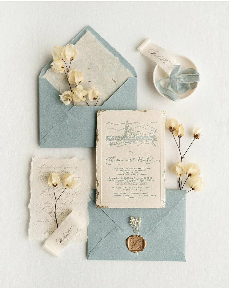 the wedding stationery is laid out on top of an envelope with flowers and wax