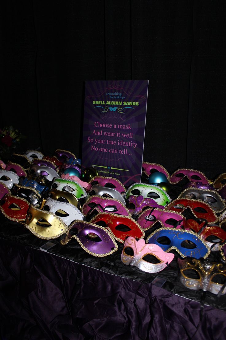 a table topped with masquerade masks and a sign