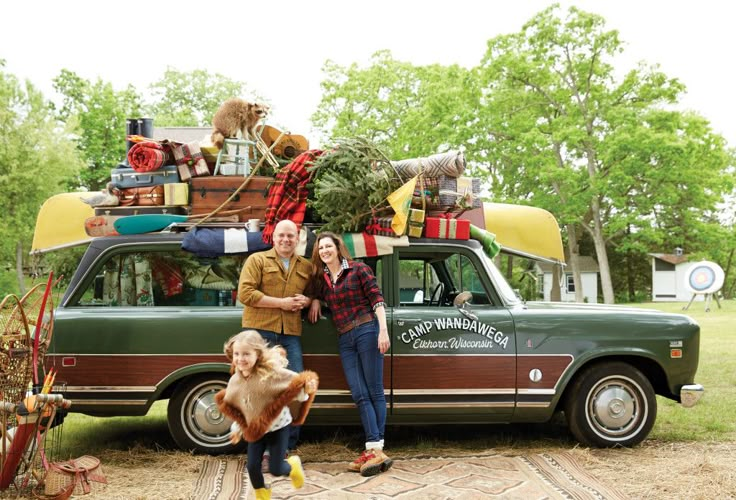 a man and woman standing in front of a car with christmas decorations on the roof