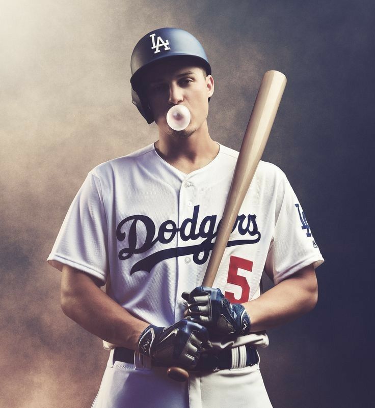 a baseball player with a bubble gum in his mouth is holding a bat and posing for the camera