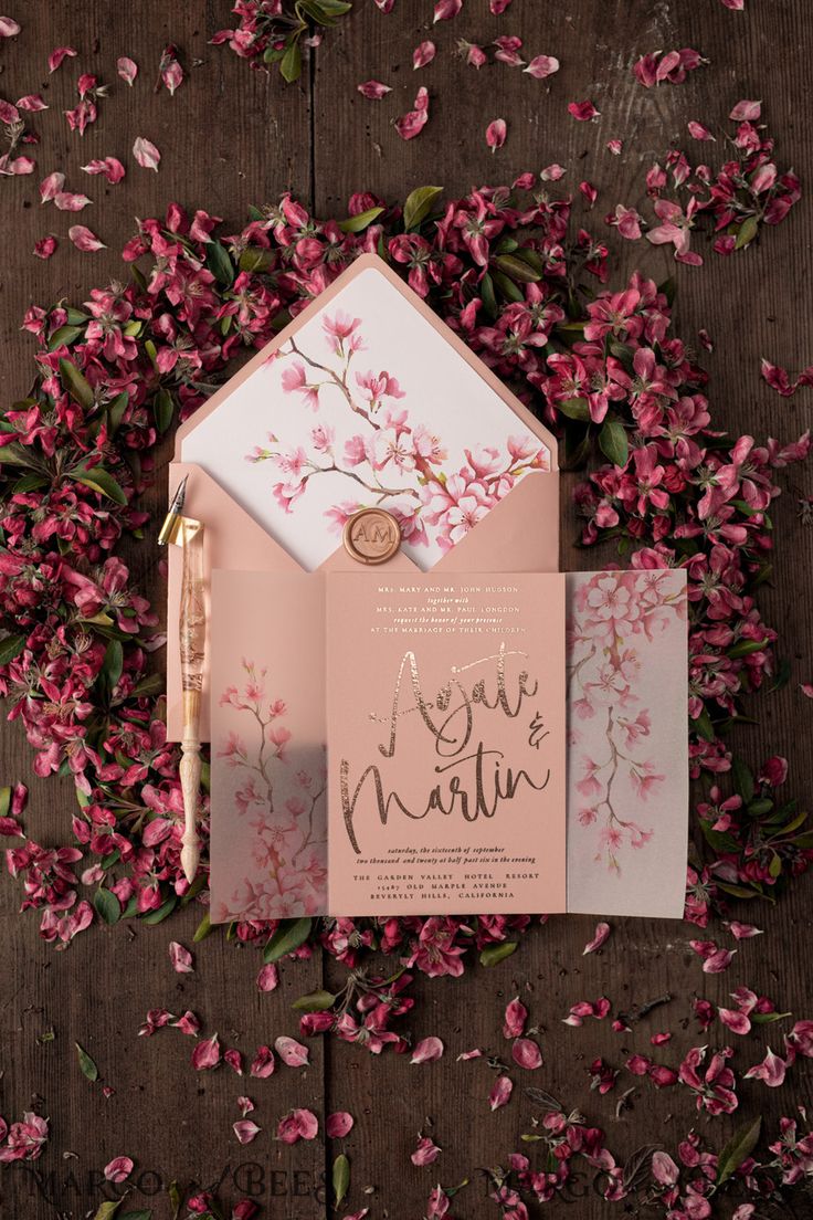 the wedding stationery is surrounded by pink flowers