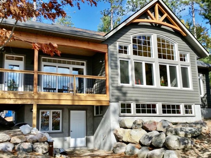 a large gray house surrounded by trees and rocks