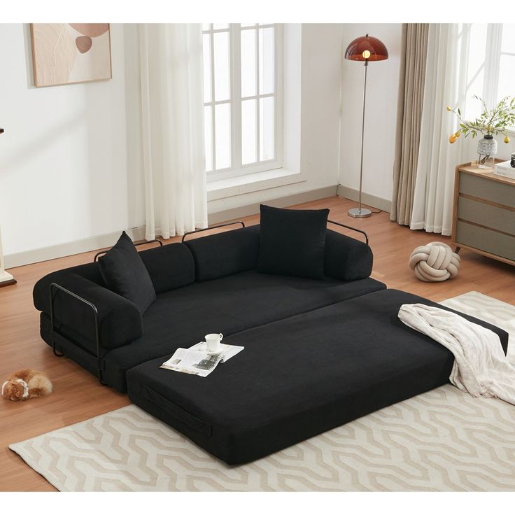 a large black couch sitting on top of a wooden floor next to a white rug