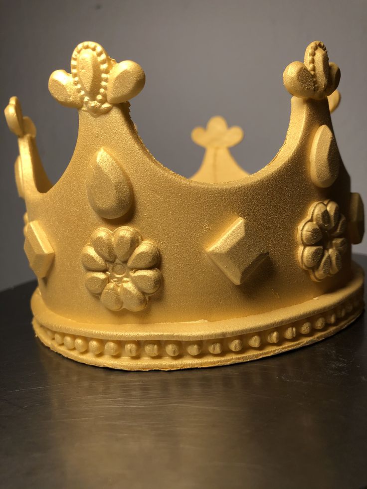 a gold colored crown sitting on top of a wooden table in front of a gray wall