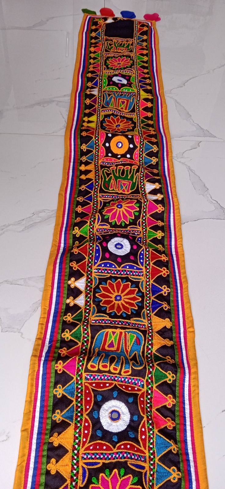 a long multicolored rug with designs on the bottom and sides, sitting on a white floor