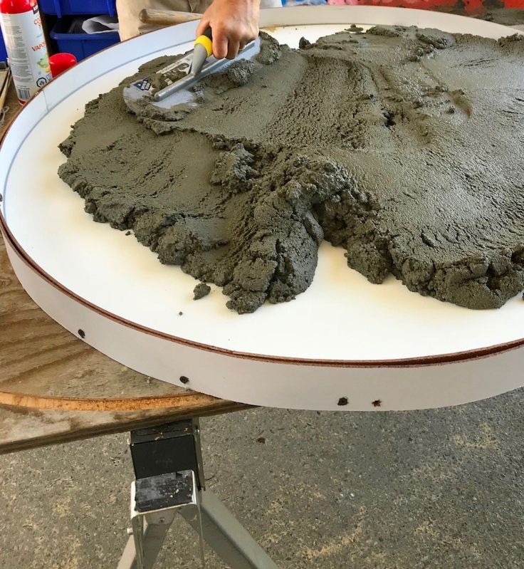 a person is spreading cement on top of a large plate with a spatula in it