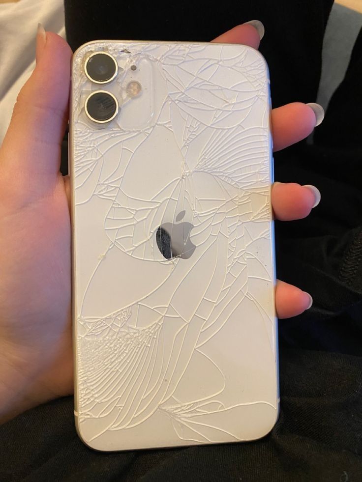 a person holding an iphone in their hand with cracked glass on the front and back