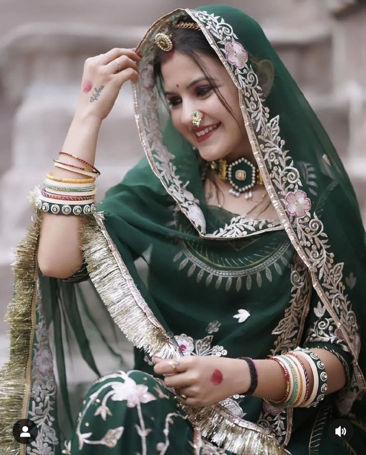 a woman in a green and gold sari with jewelry on her head is smiling at the camera