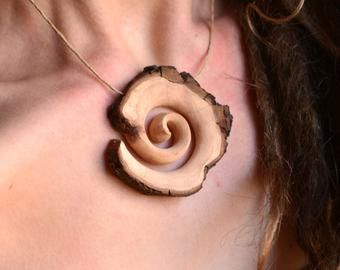 a close up of a person wearing a necklace with a wooden object in the shape of a flower