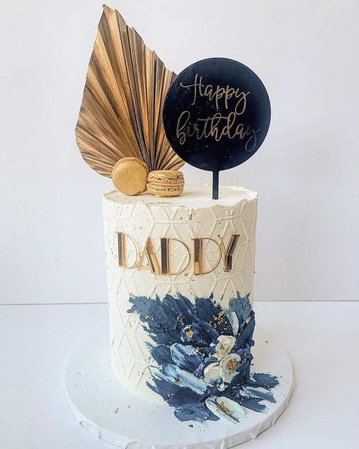 a birthday cake decorated with blue flowers and gold foiling is sitting on a white plate