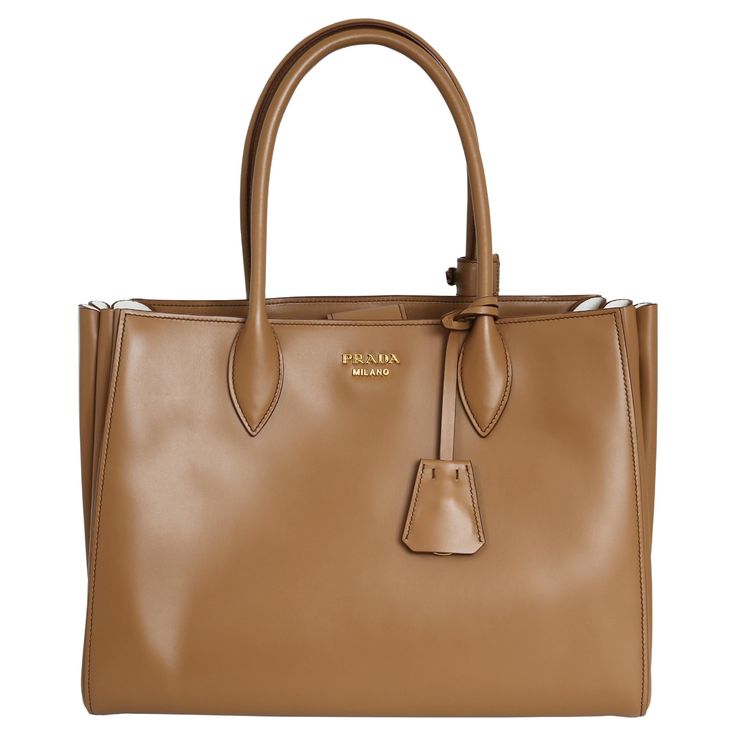 This Prada City Calf tote bag is expertly crafted from smooth calfskin leather in a warm caramel colour with talc accents. Versatile and chic, it comes with a long strap for easy wear and is brand new. 100% Calf Leather Detachable strap Spacious compartment Interior zipped pocket and slip pocket Includes original Prada dust bag Excellent condition with few signs of wear. Bags Prada, Oversized Tote Bag, Prada Bags, Caramel Color, Prada Handbags, Black Tote Bag, Bag Straps, Prada Bag, Easy Wear