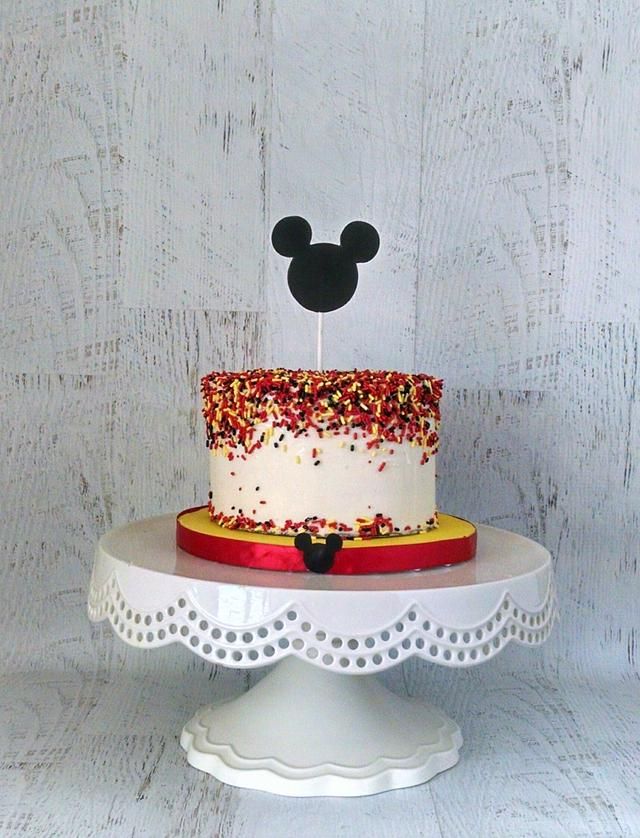 a mickey mouse cake with sprinkles and a topper on it's head