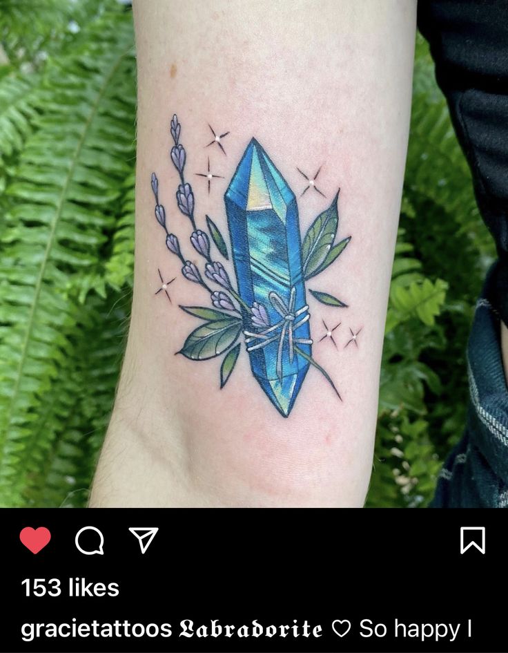 a woman's arm with a tattoo on it that has an image of a blue crystal