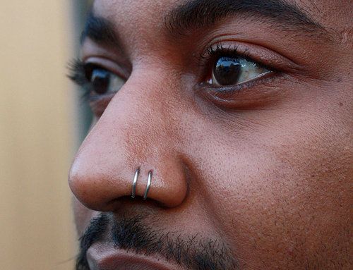 a close up of a man with piercings on his nose and nose ring in front of him