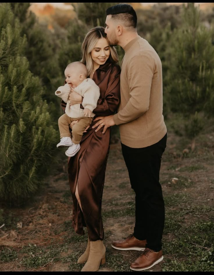 a man and woman holding a baby in their arms while standing next to each other