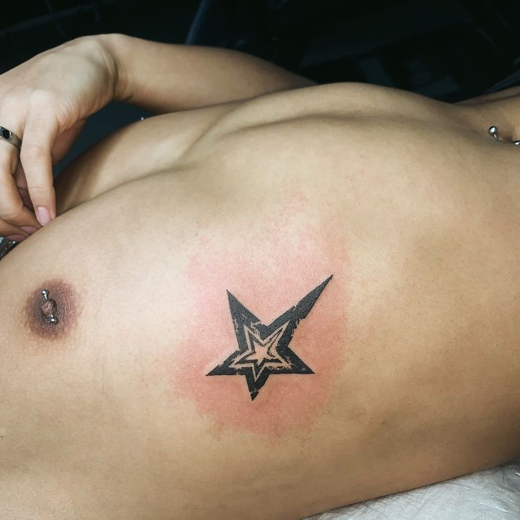 a woman with a star tattoo on her stomach is laying down and looking at the camera