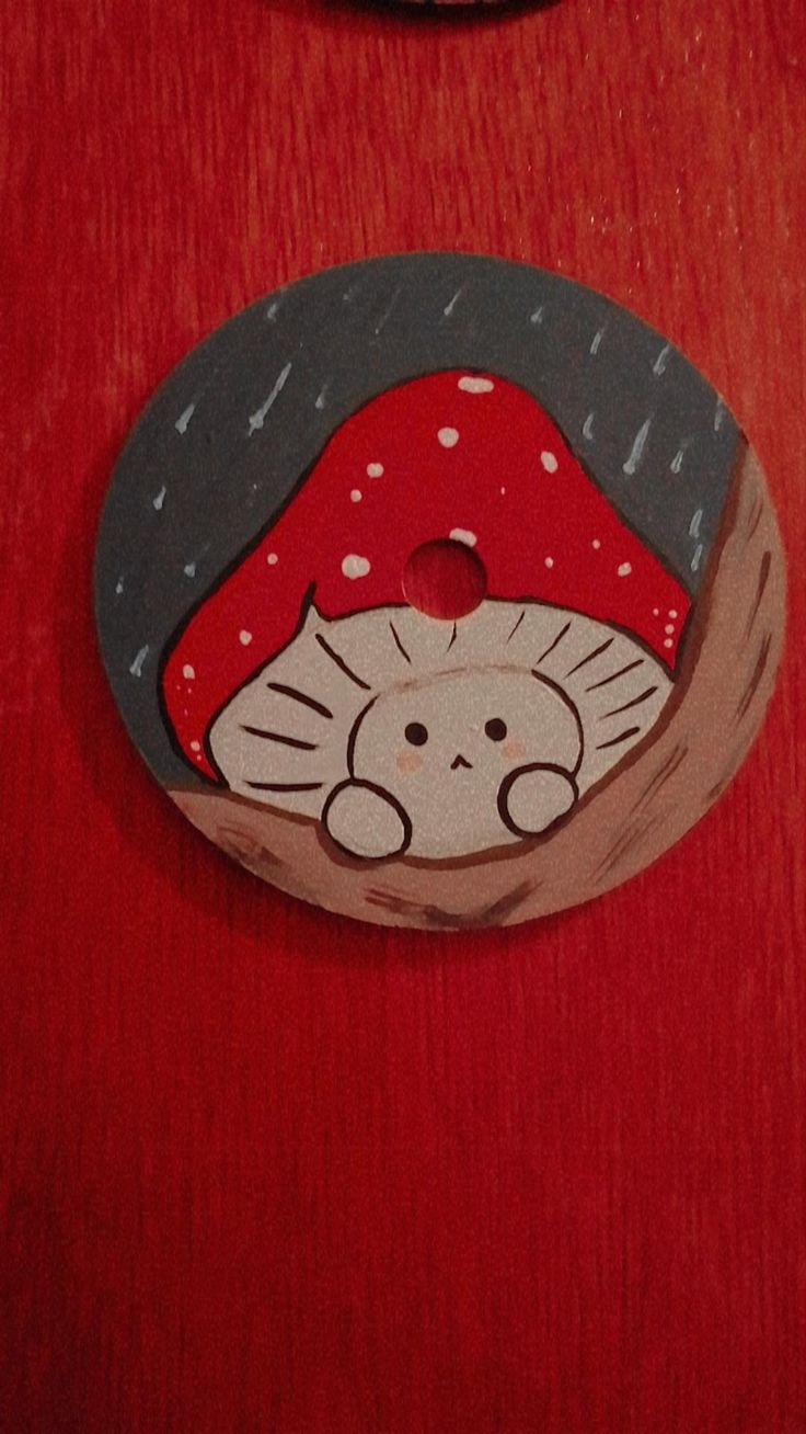 a red table with a mushroom on it and a black cat sitting in the hole